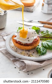 Pouring Hollandaise sauce over poached egg for cooking benedict egg for tasty breakfast. vertical orientation. English brunch