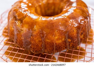 Pouring Homemade Caramel Glaze Over Freshly Baked Apple Bundt Cake.