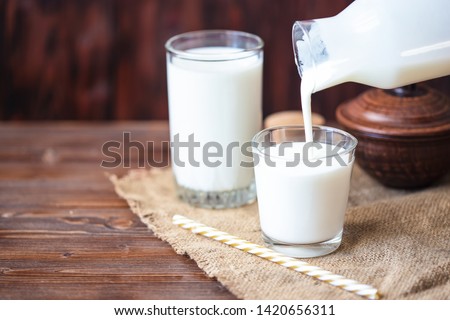 Pouring homemade kefir, yogurt with probiotics Probiotic cold fermented dairy drink Trendy food and drink Copy space Rustic style.