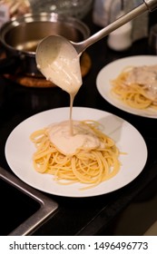 Pouring Homemade White Sauce Onto Pasta