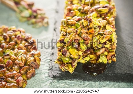 Pouring honey on traditional sugar coated pistachio sweets. Egyptian oriental dessert usually eaten during 
