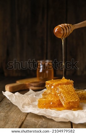 Pouring honey onto combs on wooden background