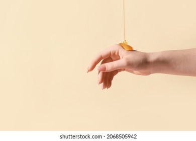 Pouring Of Honey Onto Female Hand On Color Background, Closeup