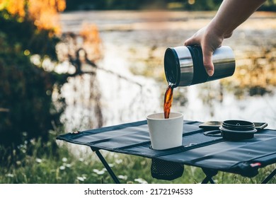 Pouring hot black coffee in reusable bamboo cup on camping table outdoors during early morning hours. Making freshly brewed coffee in nature - Powered by Shutterstock