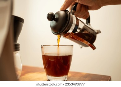 Pouring hot coffee from a french press jug into a drinking glass - Powered by Shutterstock