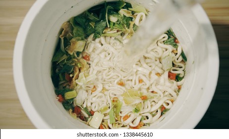 Pouring Hot Water Into Cup With Instant Noodles, Top Down View