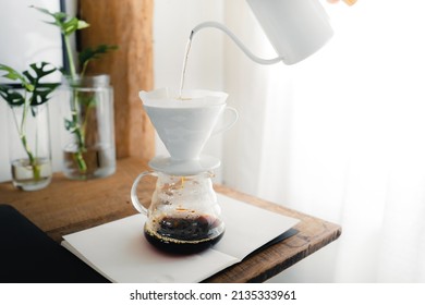 Pouring a hot water over a drip coffee on the table in the room
