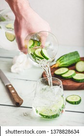 Pouring infused water with sliced cucumber