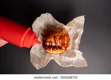 Pouring Ketchup On Melted Cheese Burger..Hands Hold Fresh Delicious Burgers With Fries, With Sauce. Fast Food Concept.