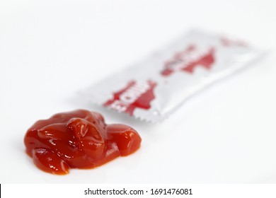 Pouring Ketchup, Red Ketchup Or Tomato Sauce With Small Silver Packaging Or Sachet Packet Isolated White Background