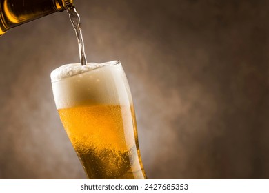 Pouring lager beer into glass with foam on dark background. - Powered by Shutterstock