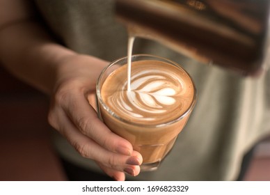 Pouring latte art into the flat white glass