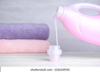 Pouring laundry detergent from bottle into cap on table, space for text - Shutterstock ID 1526149541