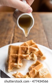 Pouring Maple Syrup Onto Plate Of Waffle