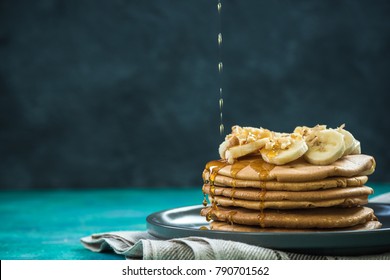 pouring maple syrup over pancakes pile, copy space image.