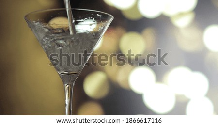 Pouring Martini into a glass. Blurred background.