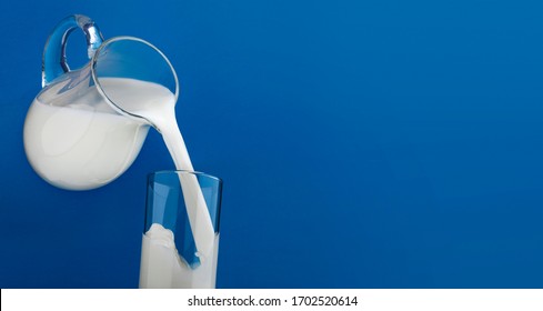 Pouring milk in glass with splash isolated on blue background with copy space for text, dairy product banner - Powered by Shutterstock