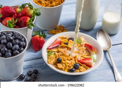 Pouring milk into cornflakes with fruits