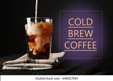 Pouring milk into glass with cold brewed coffee on black background