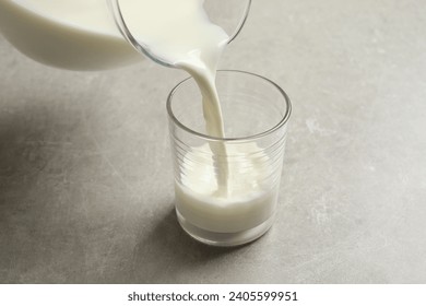 Pouring milk into glass on grey table - Powered by Shutterstock