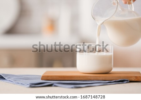 Pouring of milk into glass on table