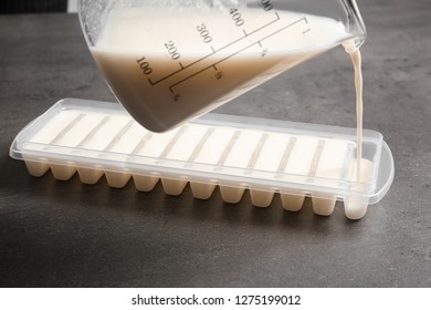 Pouring Milk Into Ice Cube Tray On Grey Table