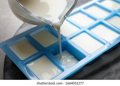 Pouring Milk Into Ice Cube Tray At Table, Closeup