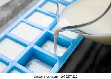 Pouring Milk Into Ice Cube Tray At Table, Closeup