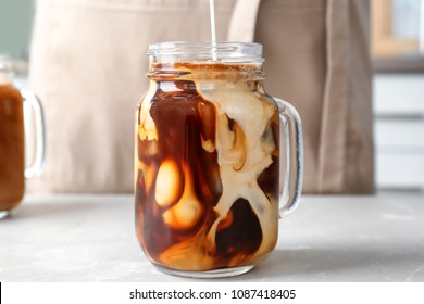 Pouring Milk Into Mason Jar With Cold Brew Coffee On Table