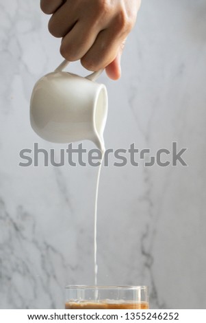 Pouring milk to tea cup,hot drink,milk in jug in white  background