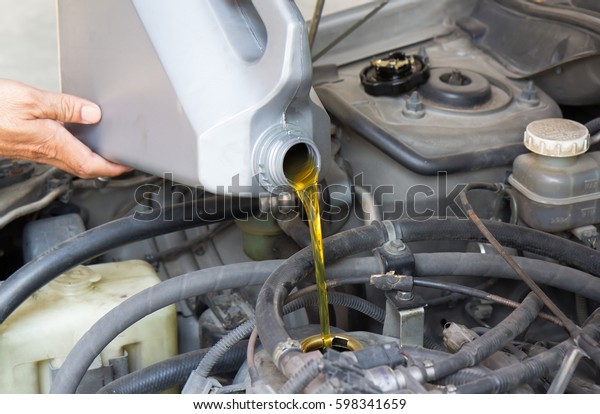 pouring motor oil to car engine, concept :\
service and maintenance