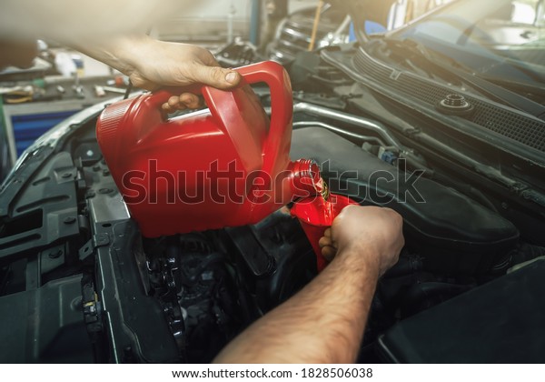 Pouring new engine oil from canister into motor\
funnel at car service, close\
up