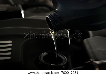 Pouring oil to car engine, close up. Selective focus.