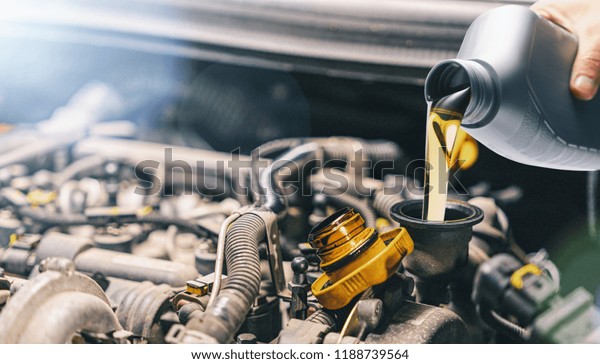 Pouring oil to car engine. Fresh motor oil poured\
during an oil change to a\
car.