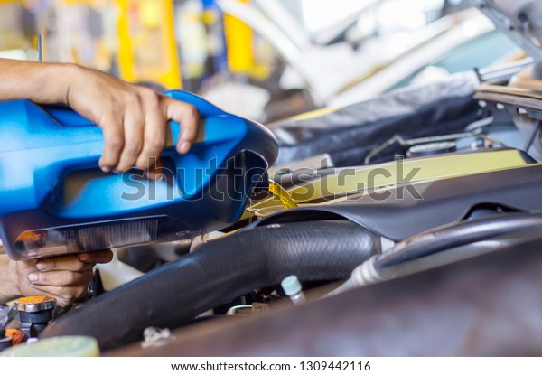 Pouring oil to car engine.\
Fresh oil poured during an oil change to a car. , close up\
selective focus 
