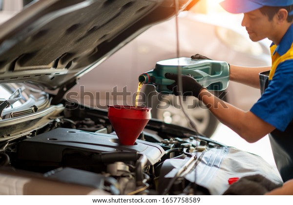 Pouring oil to car engine, Mechanic pouring oil\
into car at the repair\
garage