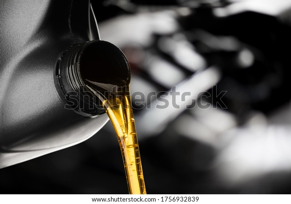 Pouring oil lubricant motor car from\
black bottle on engine background oil change auto\
shop