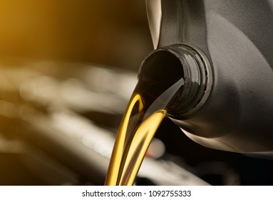 Pouring oil motor car  lubricant  from black bottle on engine background , service oil change auto repair shop 