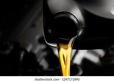 Pouring oil motor car  lubricant  from black bottle on engine background , service oil change auto repair shop 