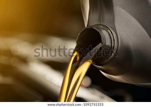Pouring oil motor
car  lubricant  from black bottle on engine background , service
oil change auto repair shop
