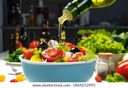 Pouring Olive oil on fresh Vegetable salad, mediterranean cuisine, Greek salad, white table served with healthy food ingredients
