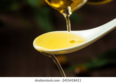 pouring olive oil in a spoon on table.