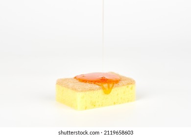 Pouring orange detergent on sponge isolated on white background. Orange liquid dish soap on sponge, home cleaning concept. Dishwashing sponge for general cleaning day - Shutterstock ID 2119658603
