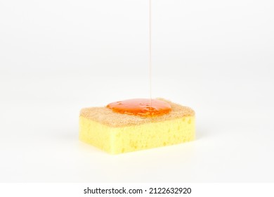 Pouring orange detergent on sponge isolated on white background. Orange liquid dish soap on sponge, home cleaning concept. Dishwashing sponge for general cleaning day - Shutterstock ID 2122632920
