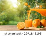 Pouring orange juice into the glass on wooden table in orange farming.