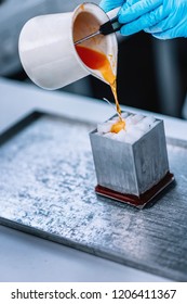 Pouring Orange Malted Wax Into Aluminum Mold Filled With White Wax Cubes Inside. Special Candle Making Process.