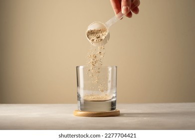 Pouring protein powder from scoop, in glass a glass. Making protein drink. - Shutterstock ID 2277704421