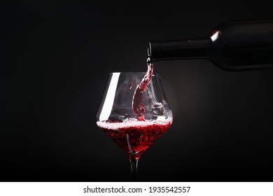 Pouring Red Wine From Bottle Into Glass On Black Background