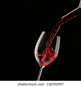 Pouring Red Wine Into Wine Glass On A Black Background