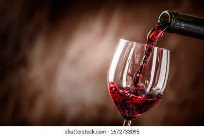 Наливание красного вина в бокал на деревенском фоне. Налейте алкоголь, концепция винодельни.